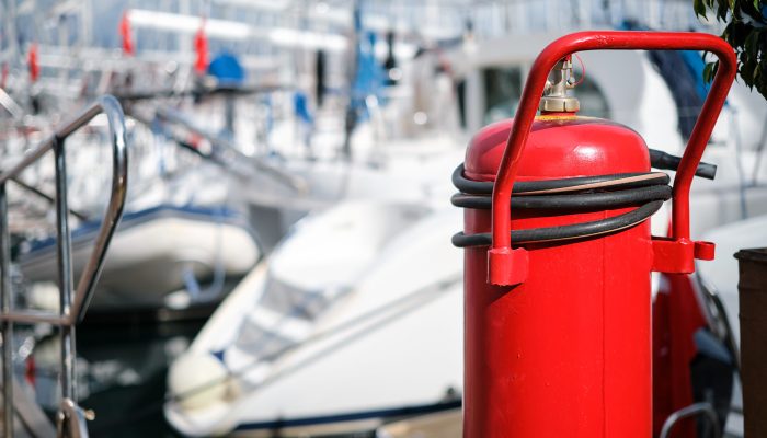 Fire extinguisher close-up on the mooring of the yacht club, blurred background. providing fire protection and safety prevention. Fire extinguisher close-up on the mooring of the yacht club, blurred background. providing fire protection and safety prevention.